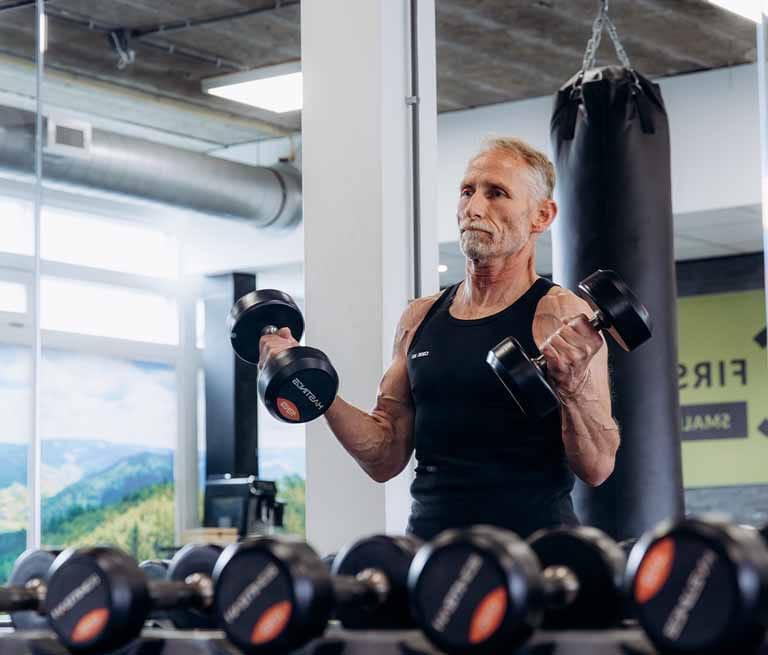 Man doet halter training in een moderne fitness studio met bokszak op de achtergrond