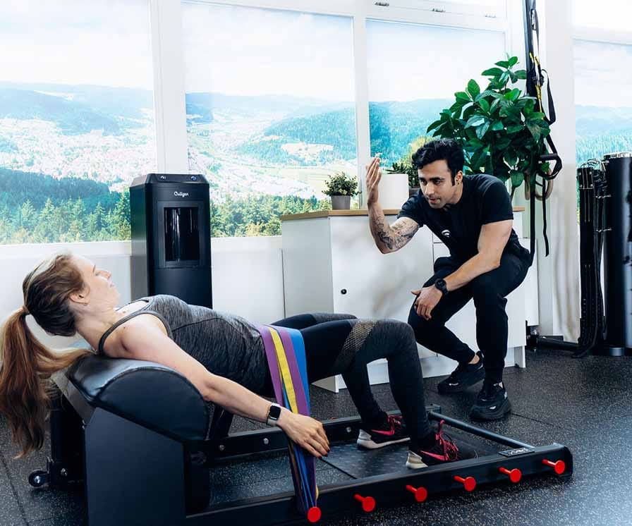 Personal trainer begeleidt vrouw bij training op roeiapparaat in moderne studio met bergpanorama