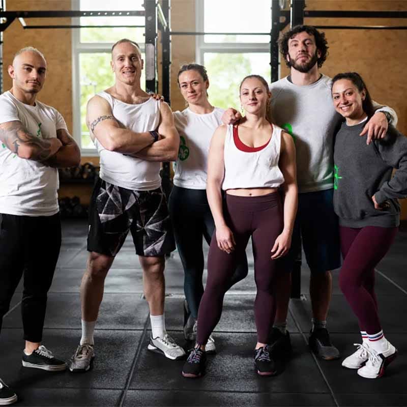 Groep van zes trainingsprofessionals en sporters in fitnesskleding in een moderne trainingsruimte