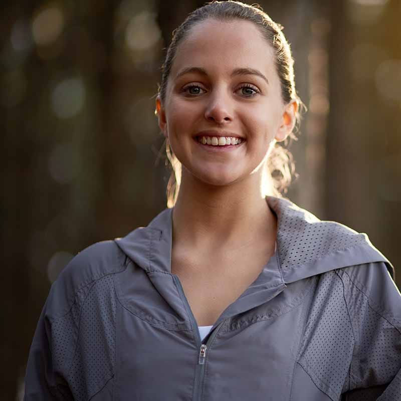 Glimlachende vrouw in grijze sportjas tijdens personal training sessie