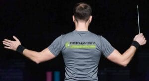 Man van achteren in grijs shirt met armen uitgespreid houdt trainingsstok vast