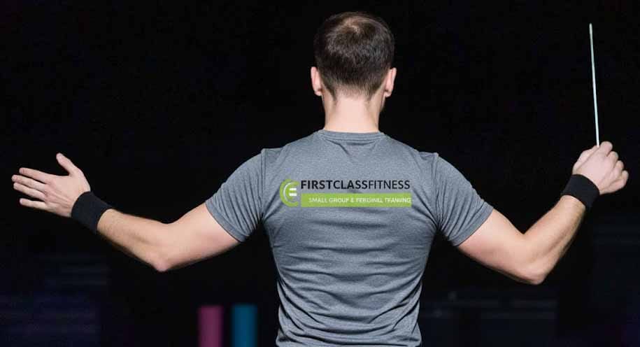 Man van achteren in grijs shirt met armen uitgespreid houdt trainingsstok vast