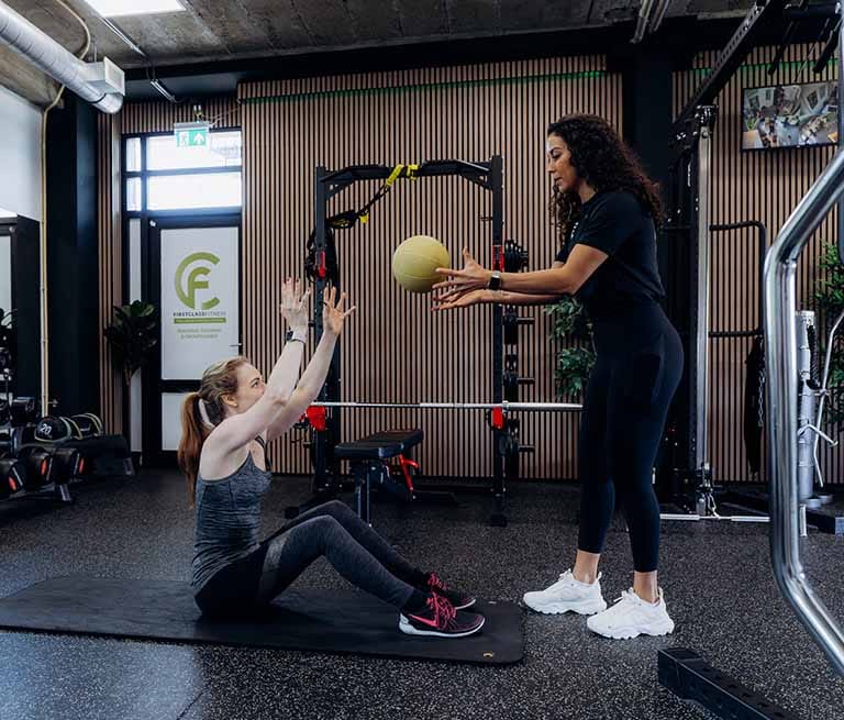Personal trainer geeft begeleiding met medicijnbal tijdens één-op-één training in de studio