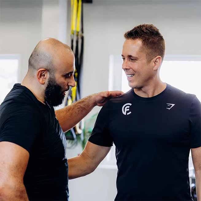 Trainer geeft aanwijzing aan cliënt tijdens personal training sessie in de studio