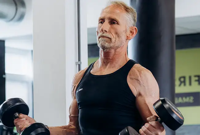 Volwassen man doet bicepsoefeningenmet halters in een fitnessruimte