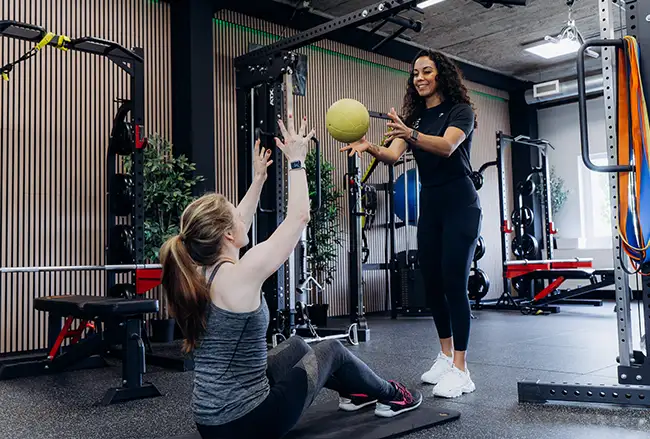 Personal trainer werkt met cliënt aan medicijnbal oefening in moderne trainings studio