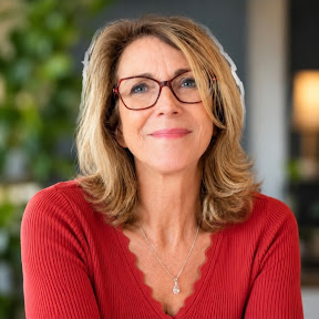 Vrouw met bril en rood shirt glimlacht naar de camera in professionele trainingsstudio