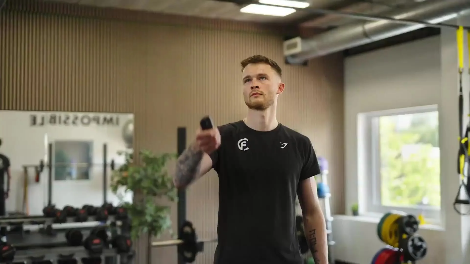 Gele binnensignage met donkergrijs logo en tekst 'SMALL GROUP & PERSONAL TRAINING' in moderne fitnessruimte